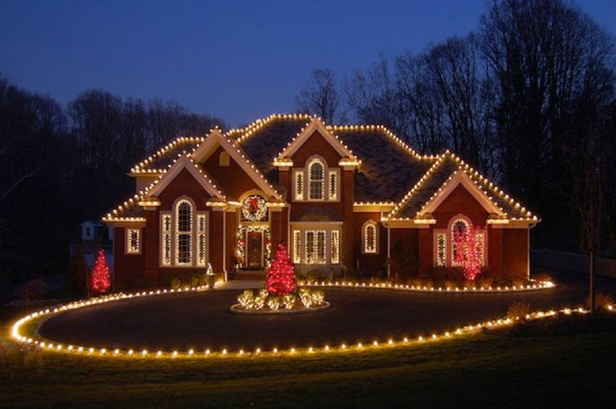 Large brick home with roofline lights and lit red trees